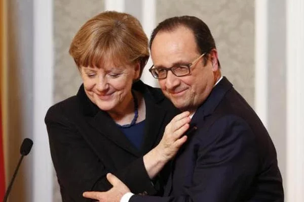 Ангела Меркель и Франсуа Олланд позируют для фотографов после изнурительных 16-часовых ночных переговоров. Фото Рейтер.