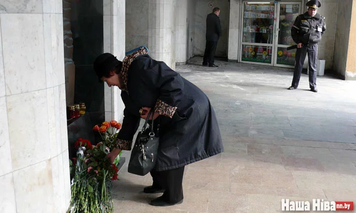 Людзі нясуць кветкі да мемарыяльнага знака каля ўваходу на станцыю метро «Кастрычніцкая».