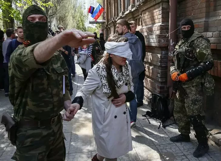 На фото: боевики в Славянске ведут задержанную украинскую журналистку.
