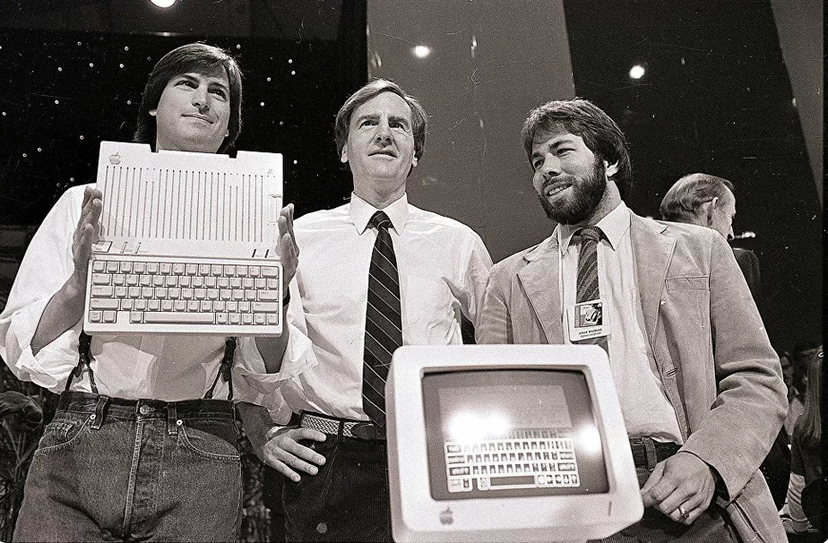 Злева направа: Стыў Джобс, Джон Скалі і Стыў Вазняк падчас прэзентацыі новага камп'ютара кампаніі Apple II ў Сан-Францыска, ЗША. 24 красавіка 1984 года