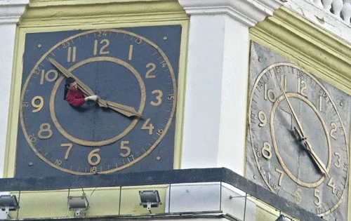 Гадзіннікар пераводзіць стрэлкі вежавага гадзінніка над праспектам Скарыны. Фота Юліі Дарашкевіч.