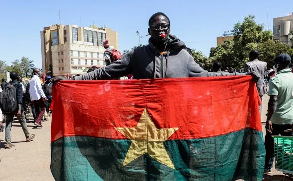Мужчина держит национальный флаг в знак поддержки военных (Фото: Vincent Bado / Reuters)