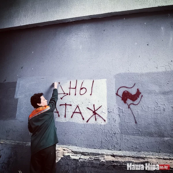 Сотрудник коммунальной службы оперативно замалевывает протестное граффити в арке дома на проспекте Независимости.