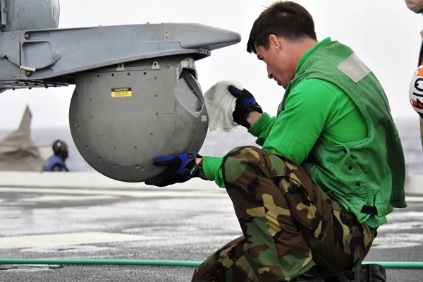 Ваенны тэхнік чысціць інфрачырвоную камеру верталёта MH-60S Sea Hawk на палубе дэсантнага транспарта-дока «Кліўленд» (LPD-7); фота nrl.navy.mil