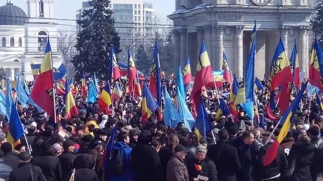 Участники акции держат в руках румынский и молдавский флаги и скандируют 