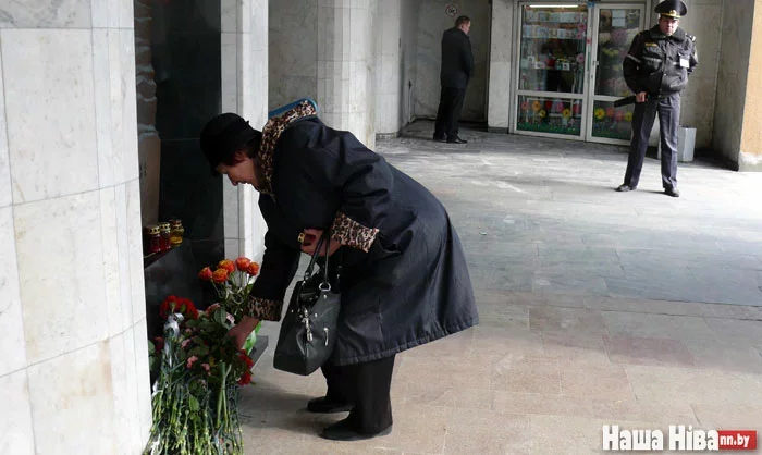 Люди приносят цветы к мемориальному знаку у входа на станцию ​​метро «Октябрьская».