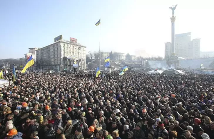Пятница, день: десятки тысяч протестующих на Майдане слушают выступление группы офицеров милиции, публично перешедших на сторону народа. Фото Рейтер.