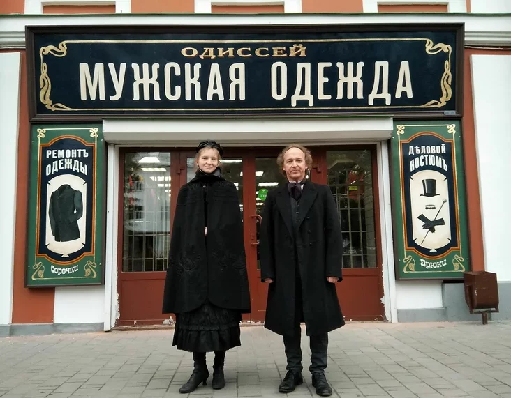 Авторы проекта в Рыбинске на фоне обновленной (состаренной) вывески магазина мужской одежды. Фото: Wikimedia Commons