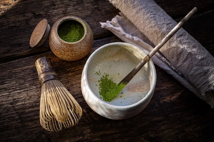 matcha tea in cup and bamboo whisk on the table