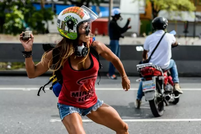 44-летняя жительница Каракаса бросает камень в полицию. Фото Univision.