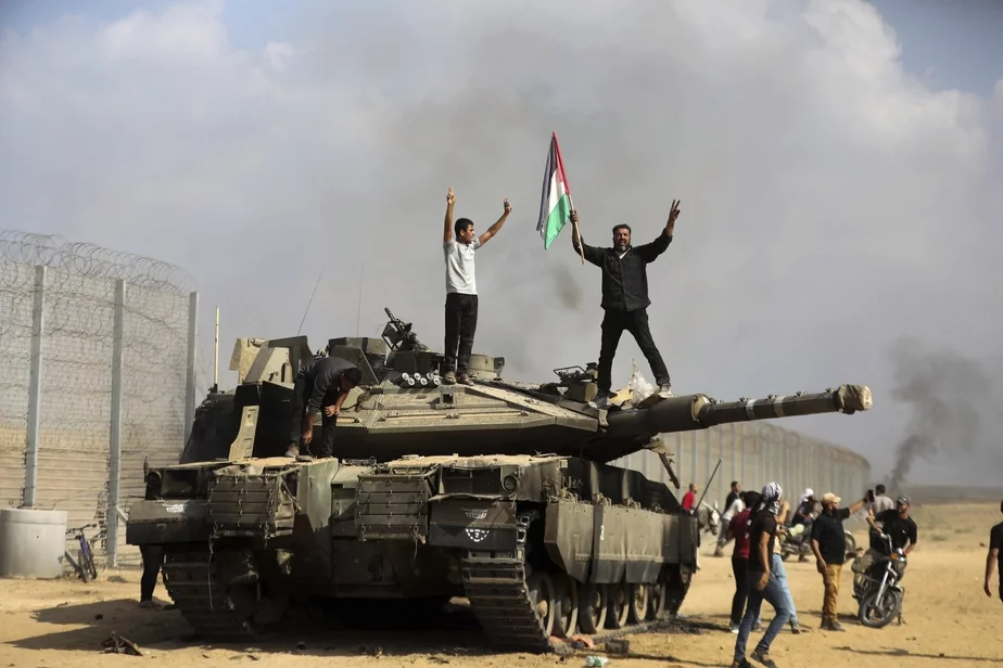 Палестинцы празднуют на подбитом израильском танке возле ограждения сектора Газа к востоку от города Хан-Юниса, 7 октября. Фото: AP Photo / Yousef Masoud