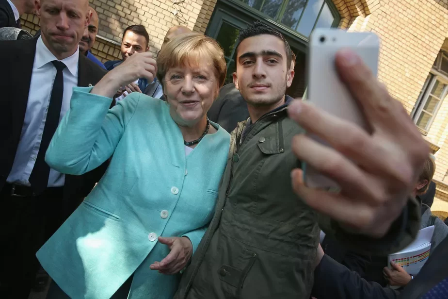 На фота: Бежанец у Берліне робіць сэлфі з Ангелай Меркель.