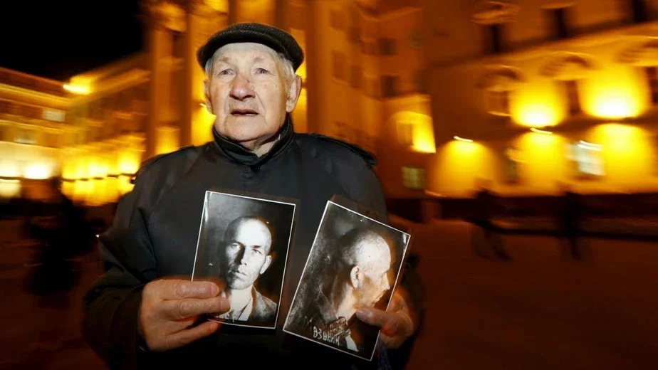 Житель Минска с портретом замученного чекистами отца возле здания КГБ в Минске.