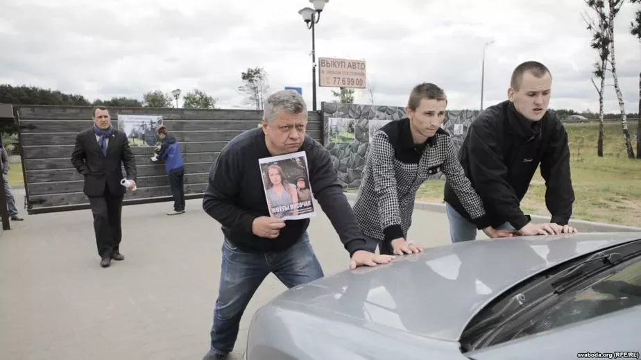 Режиссер Алексей Турович (слева перед машиной) и другие протестующие не пропускают автомобиль в ресторан «Поедем, поедим».