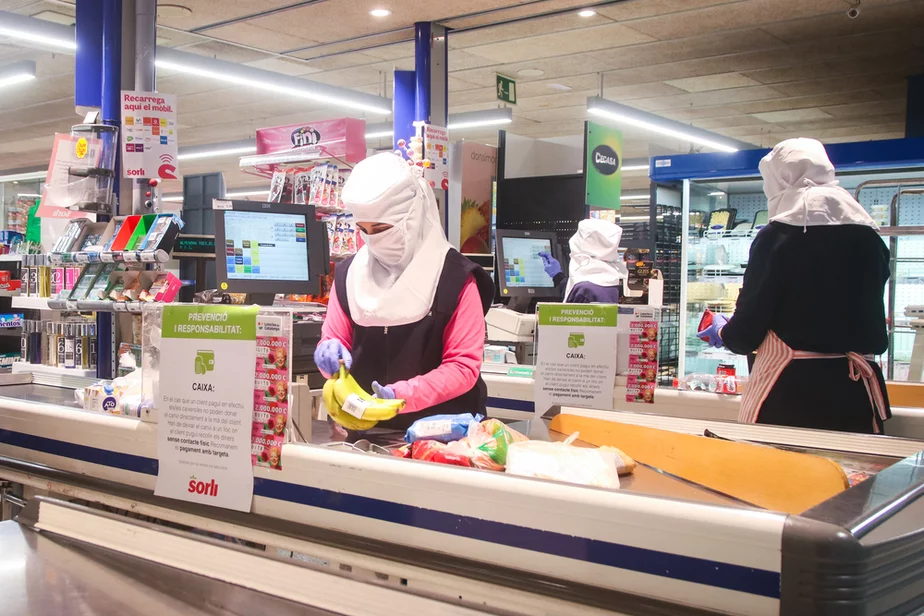 Продавцы в супермаркете Матаро, Каталония, работают в защитных костюмах. Фото Daniel Ferrer Paez, Shutterstock.com.