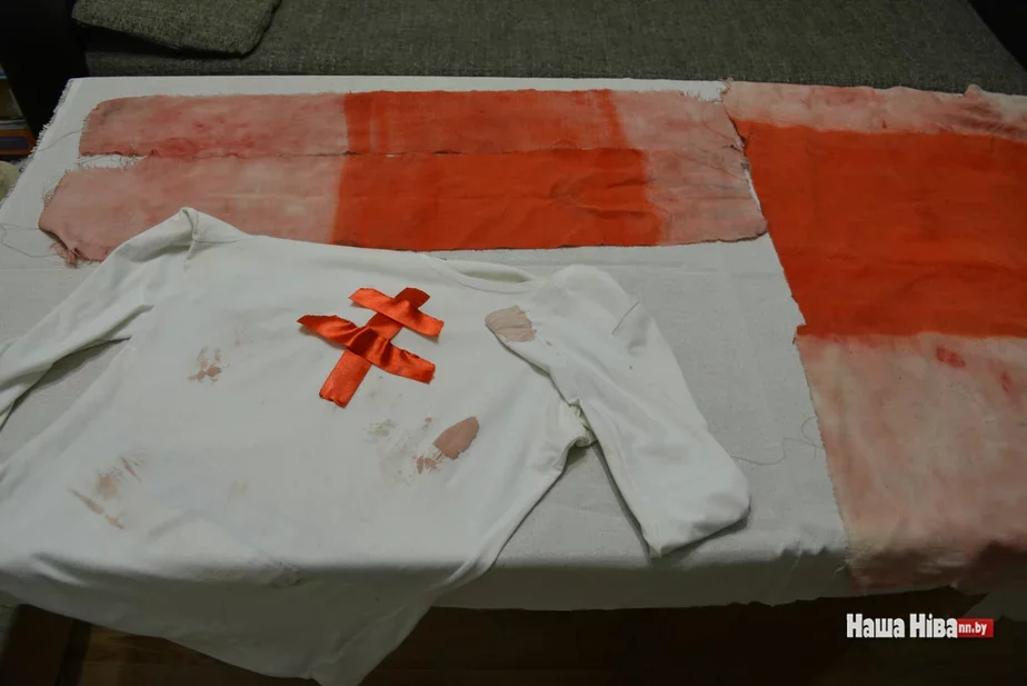 Разодранный окровавленный национальный флаг. Женщина вынесла его на себе, под дождем кровь перешла на ее блузку