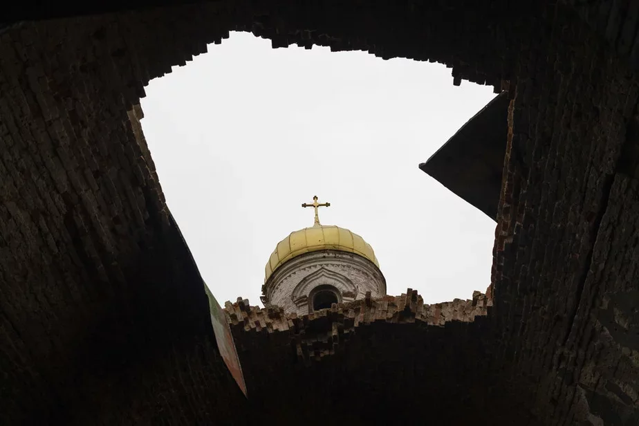 Дыра в крыше поврежденной церкви в селе недалеко от Чернигова, 22 апреля 2022 года. Внутри церкви остался единственный металлический крест из битого кирпича и почерневшего камня. Фото: AP Photo/Petros Giannakouris