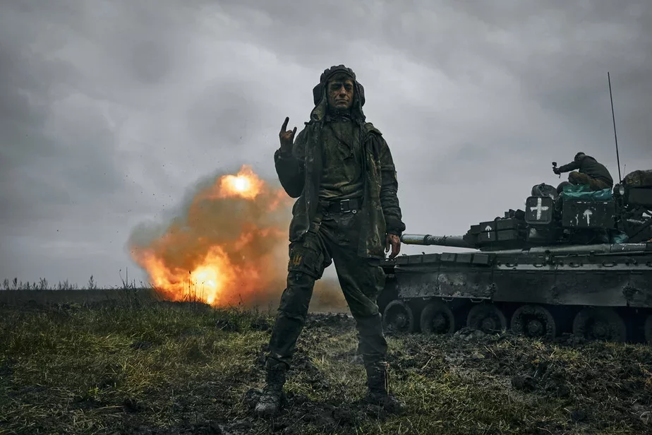 Украинский солдат позирует на фоне подбитого российского танка Т-80. Фото: AP Photo/LIBKOS
