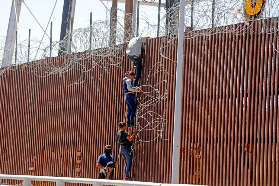 Мигранты штурмуют стену на границе с США. Иллюстративный снимок. Фото: Gary Coronado / Los Angeles Times via Getty Images