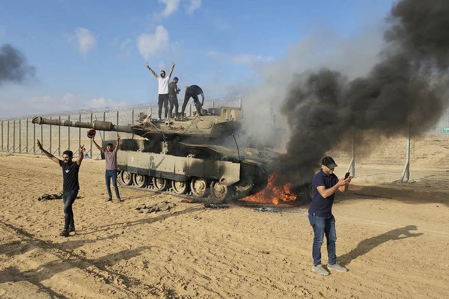 Палестинцы празднуют у уничтоженного израильского танка у ограды сектора Газа к востоку от Хан-Юниса в субботу, 7 октября. Фото: Hassan Eslaiah / AP