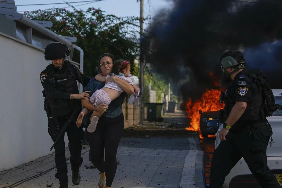 Полицейские эвакуируют женщину с ребенком в Ашкелоне после ракетной атаки из сектора Газа, в субботу, 7 октября 2023 года. Фото: Tsafrir Abayov / AP