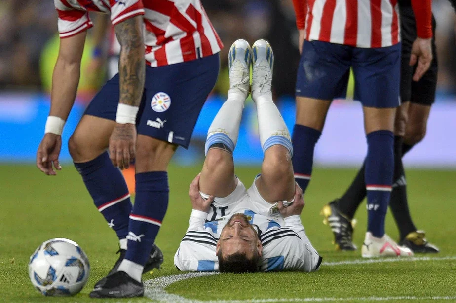 Лионель Месси лежит на спине после контакта с игроком сборной Парагвая. Фото: Gustavo Garello / AP